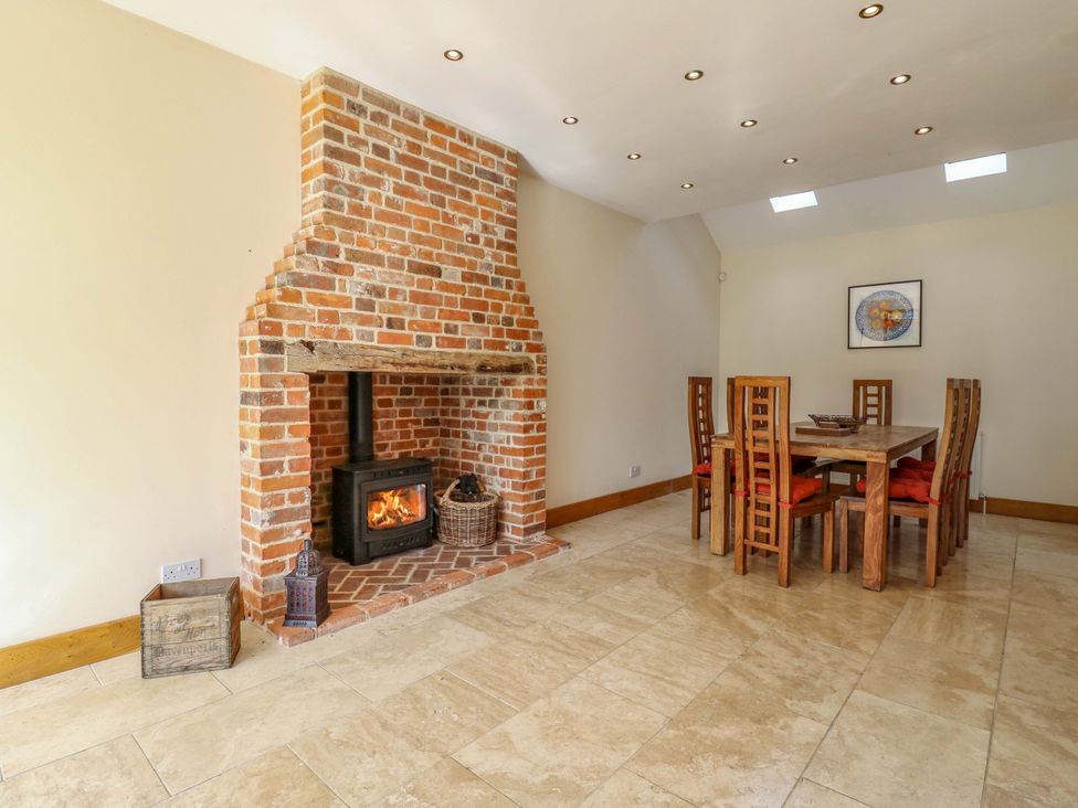 A dining room with a fireplace and dining table at Six Apples in Wethersfield near Finchingfield