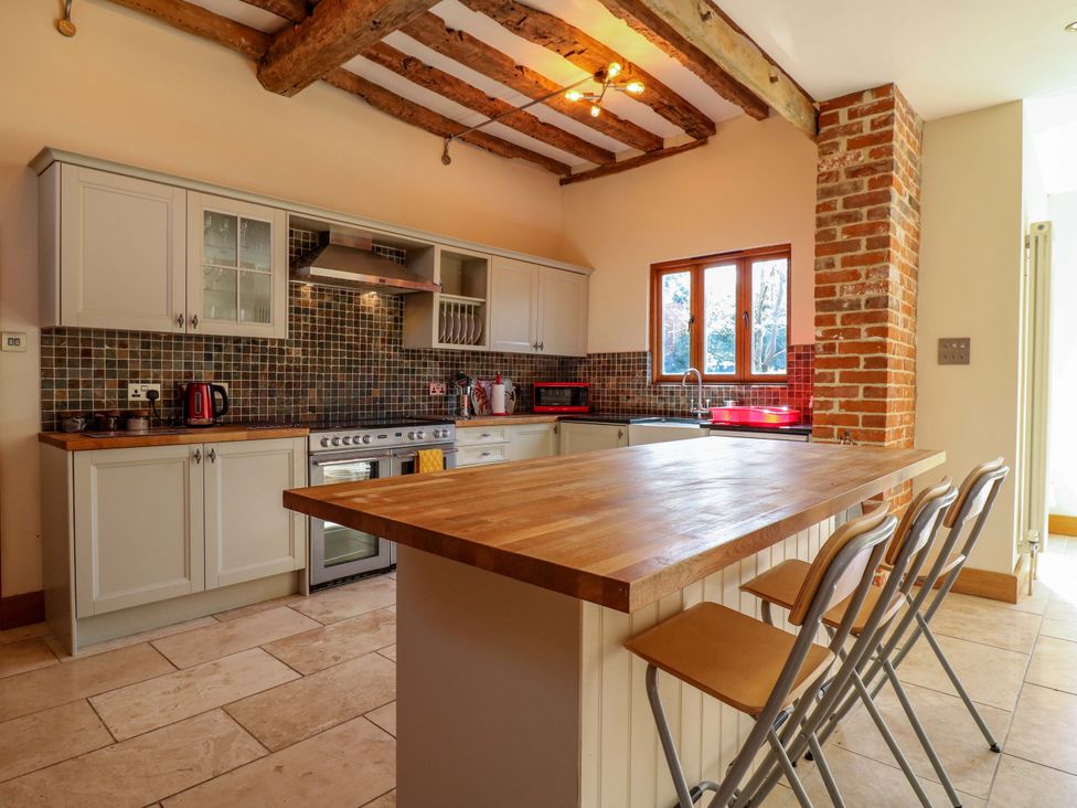 A kitchen with wooden cabinets and a large countertop at Six Apples in Wethersfield near Finchingfield