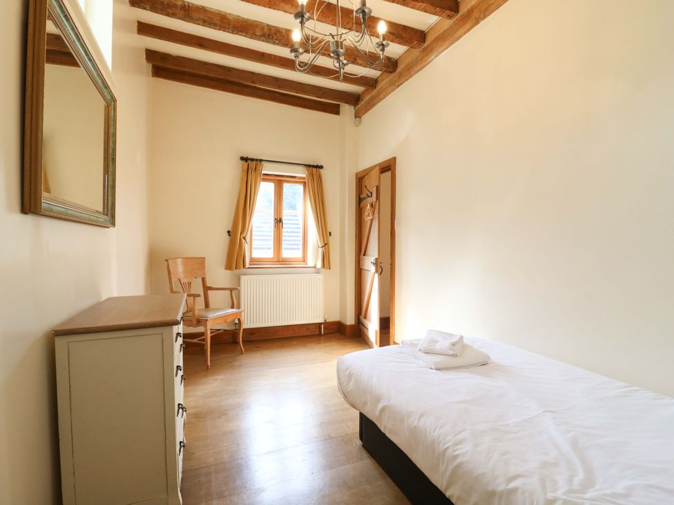 A bedroom with a bed and a chair at Six Apples in Wethersfield near Finchingfield