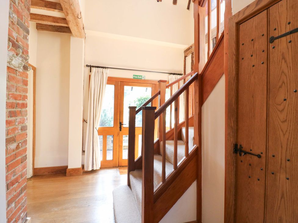 A hallway with a staircase and door at Six Apples in Wethersfield near Finchingfield