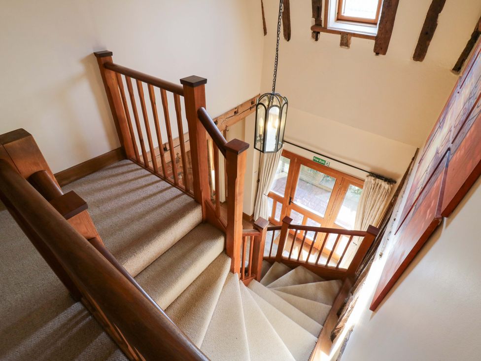 A staircase with wooden handrail and window at Six Apples in Wethersfield near Finchingfield