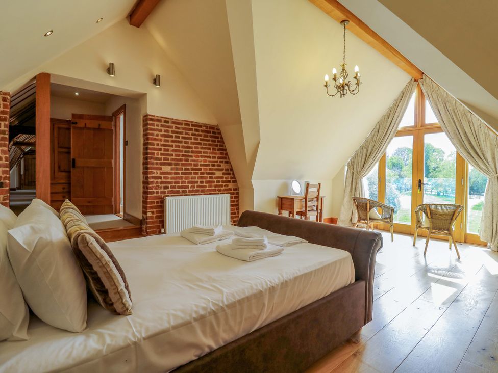 A bedroom with a bed and chairs at Six Apples in Wethersfield near Finchingfield