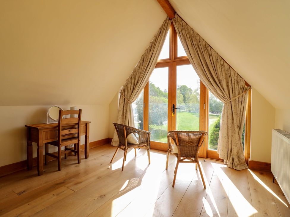 An attic with a window, table and chairs at Six Apples in Wethersfield near Finchingfield