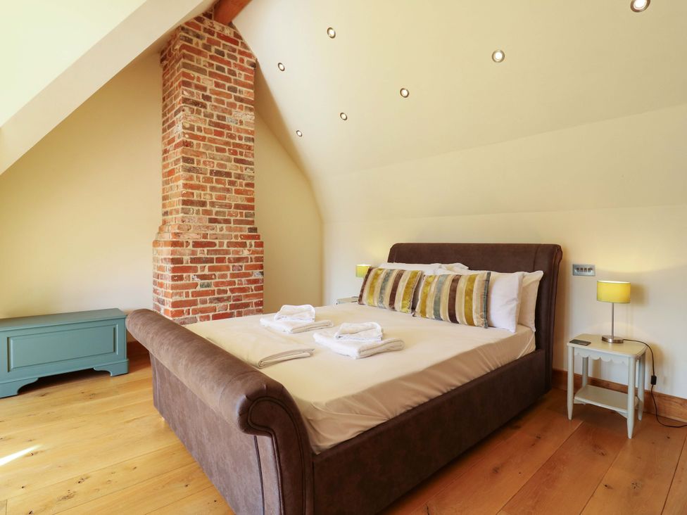 A bedroom with a bed and brick wall at Six Apples in Wethersfield near Finchingfield