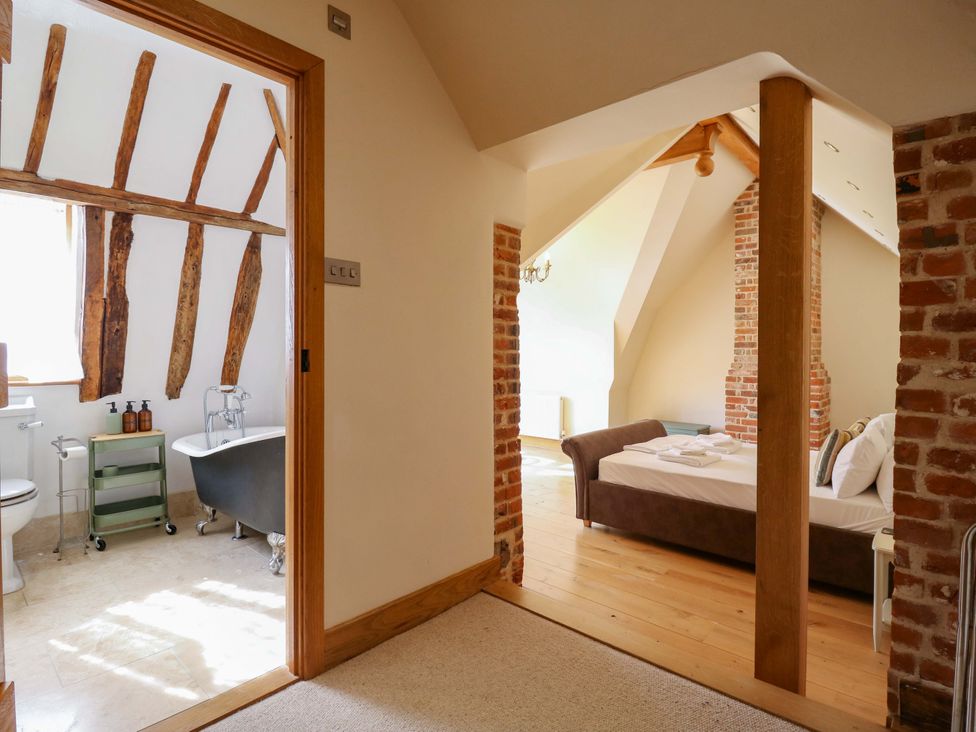 A bathroom with a bathtub and a bedroom with a bed at Six Apples in Wethersfield near Finchingfield