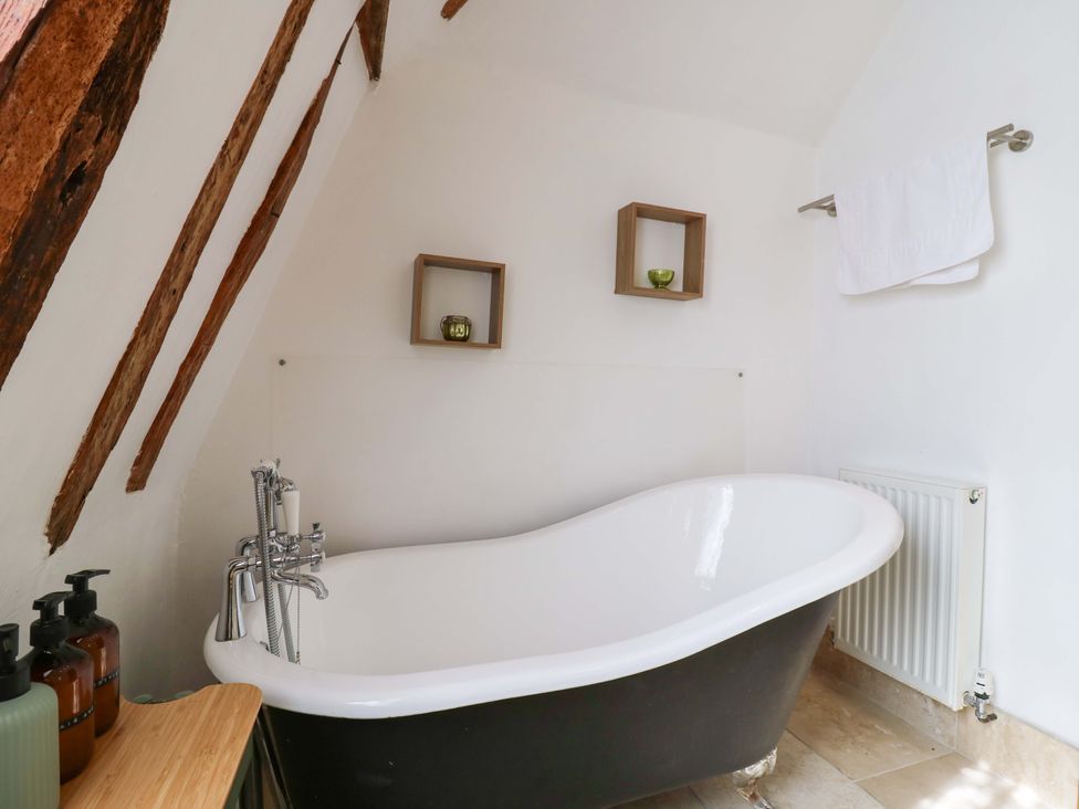 A bathroom with a bathtub and shelf at Six Apples Wethersfield near Finchingfield