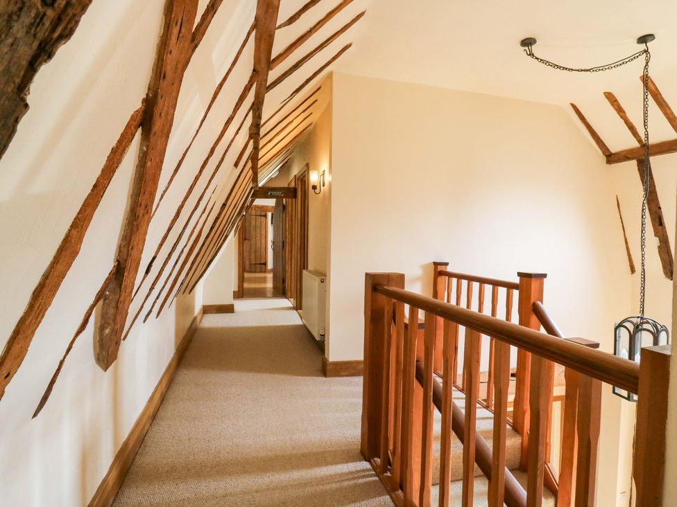 A hallway with wooden railing and light fixture at Six Apples in Wethersfield near Finchingfield