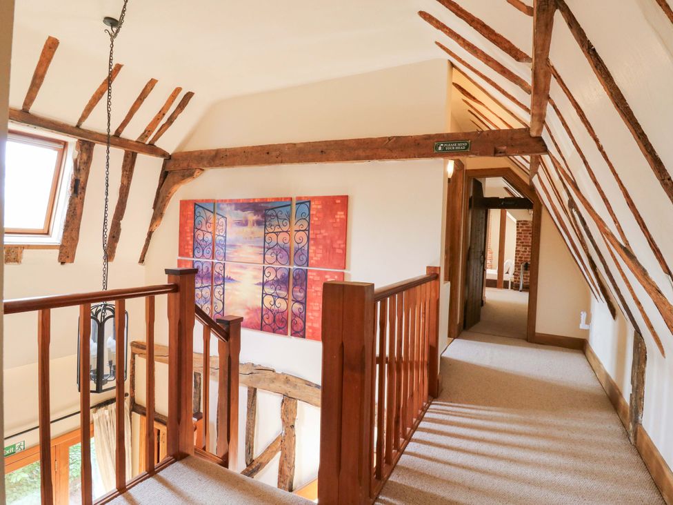 A hallway with a staircase and artwork on the wall at Six Apples in Wethersfield near Finchingfield