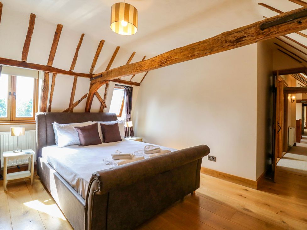 A bedroom with a bed and windows at Six Apples Wethersfield near Finchingfield