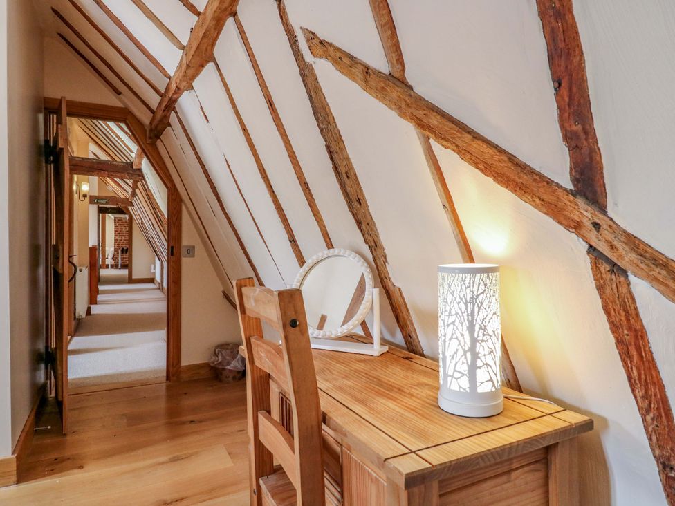 A hallway with a lamp and wooden furniture at Six Apples in Wethersfield near Finchingfield