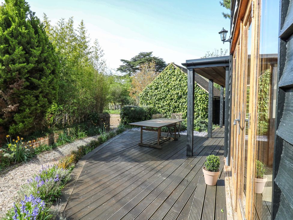A deck with a table and chairs surrounded by plants at Six Apples in Wethersfield near Finchingfield