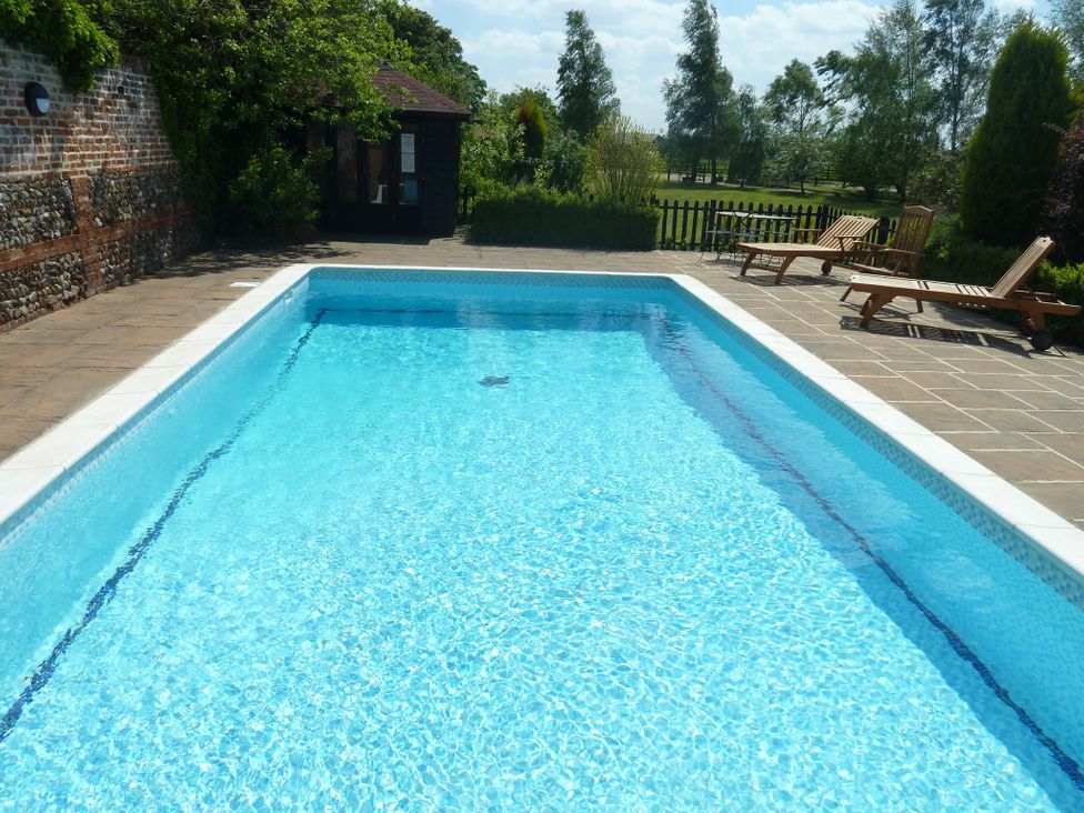 An outdoor swimming pool with deck chairs at Six Apples in Wethersfield near Finchingfield