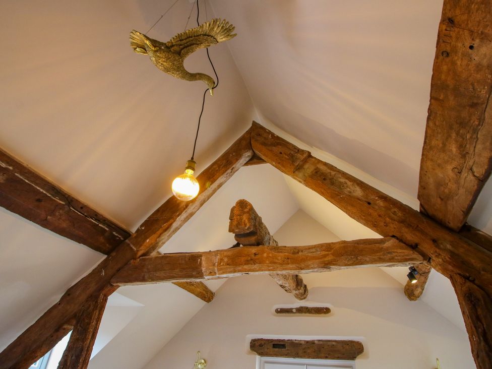 A ceiling with wooden beams and a light fixture at The Barn at Tytchney near Ombersey and Droitwich Spa