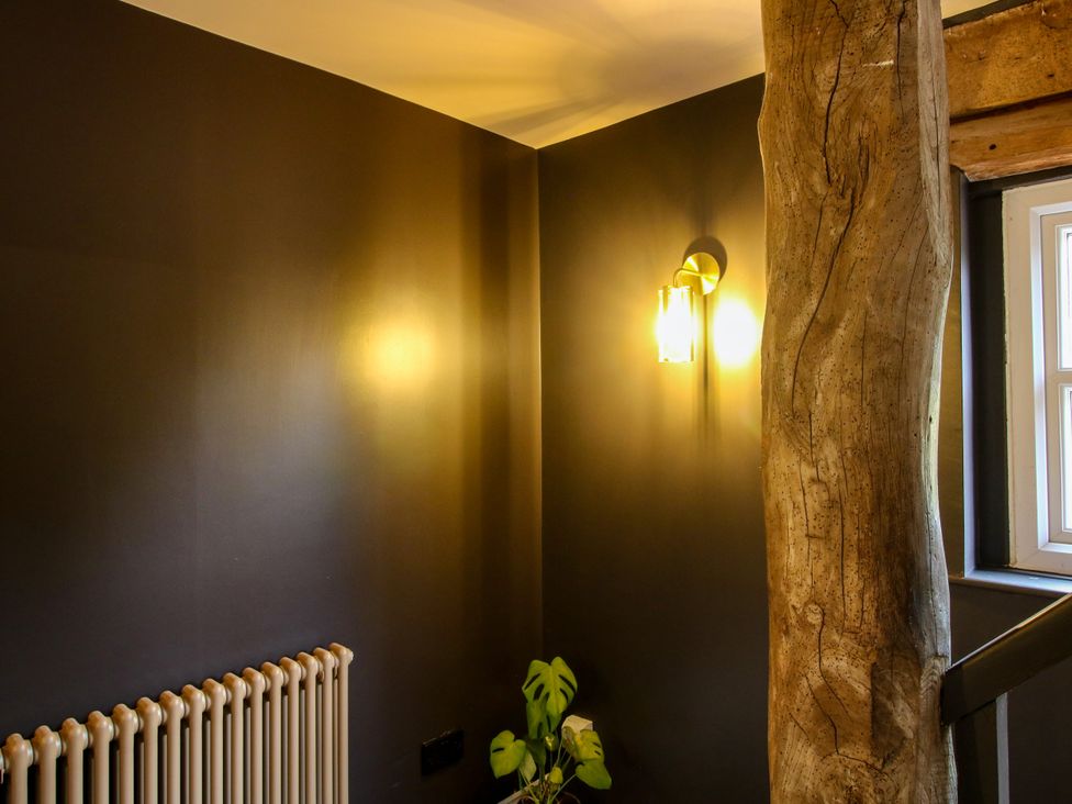 A stairway with a radiator, light, wood column, and plant at The Barn at Tytchney near Ombersey and Droitwich Spa