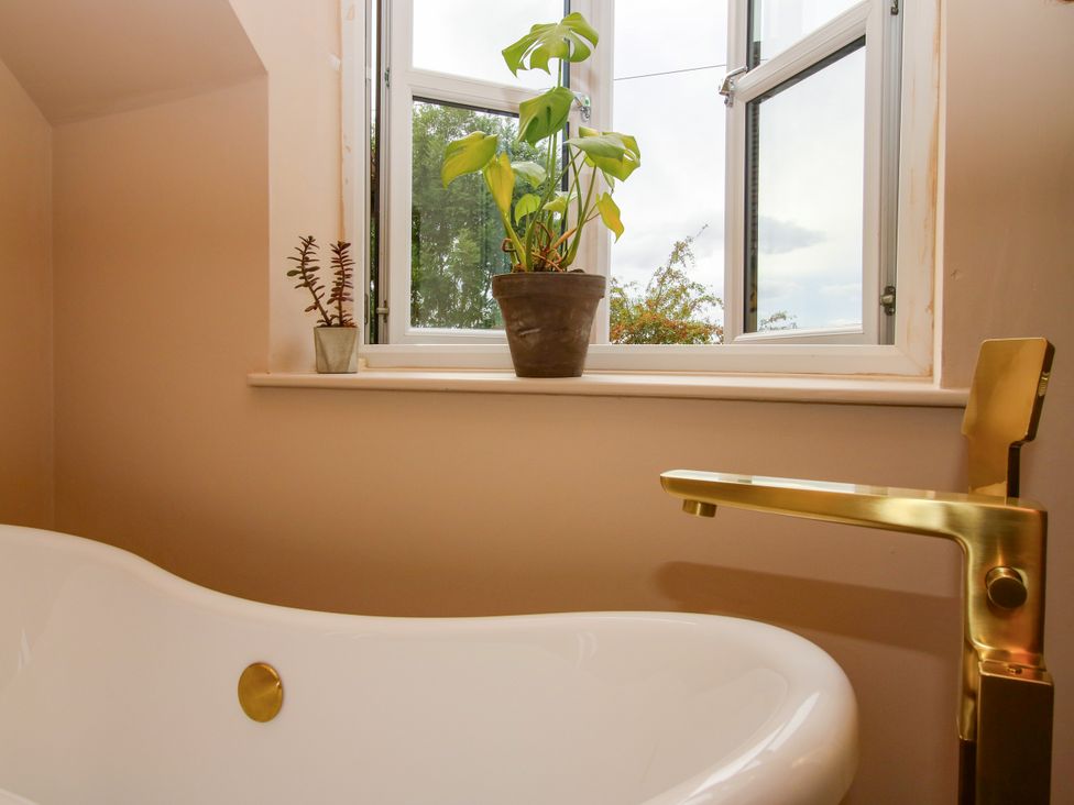 A bathroom with a bathtub, faucet, and potted plants at The Barn at Tytchney near Ombersey and Droitwich Spa