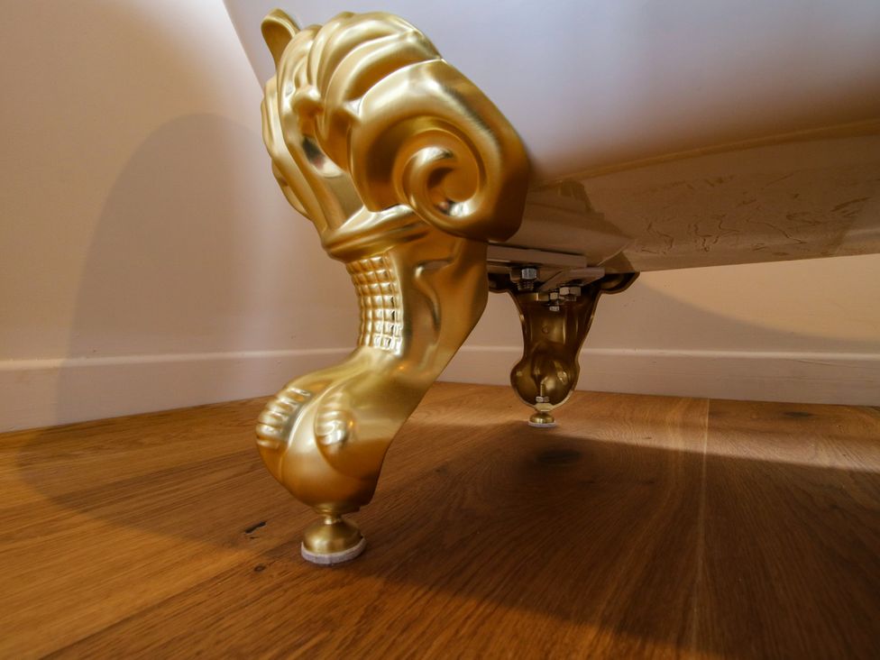 A bathtub with golden feet on a wooden floor at The Barn at Tytchney near Ombersey and Droitwich Spa