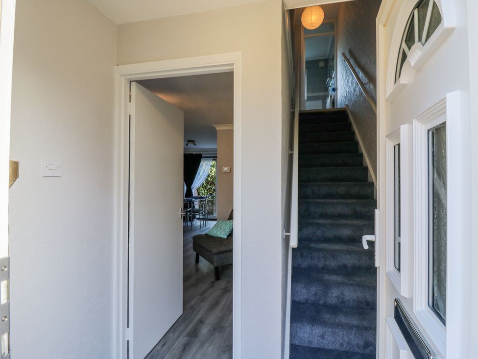 A hallway with a staircase and an open door at Sea Rose Cottage