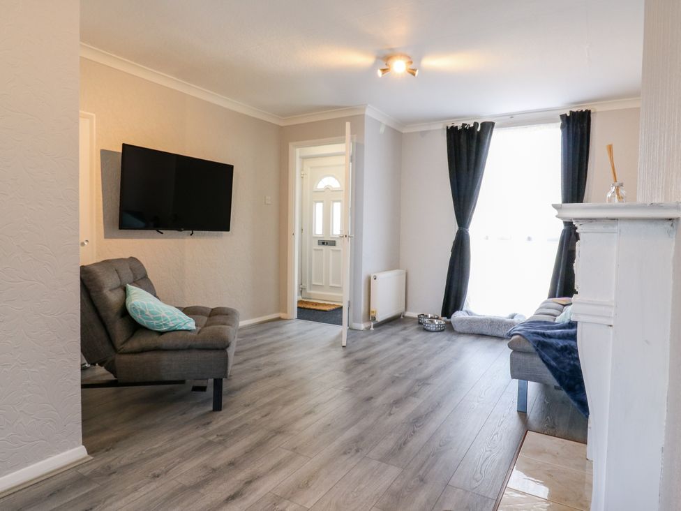 A living room with a sofa and television at Sea Rose Cottage