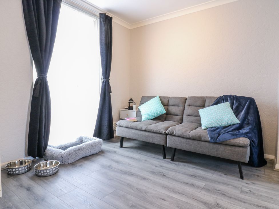 A living room with a sofa and cushions at Sea Rose Cottage