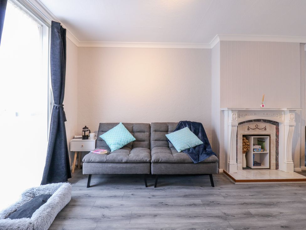 A living room with a sofa and a fireplace at Sea Rose Cottage