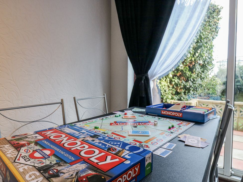 A dining room with a Monopoly board game on the table at Sea Rose Cottage