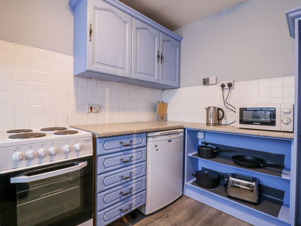 A kitchen with an oven, fridge, kettle, and microwave at Sea Rose Cottage