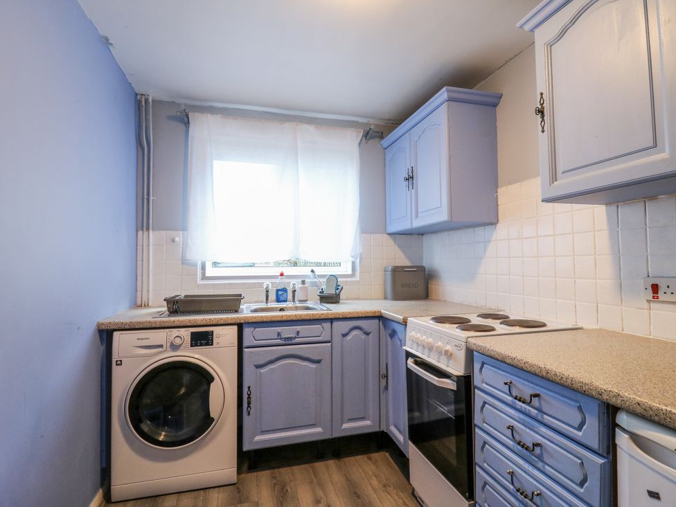 A kitchen with washing machine and oven at Sea Rose Cottage