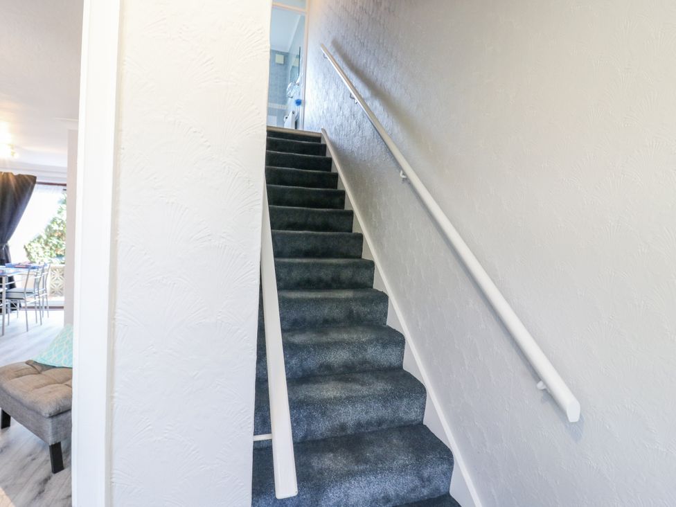 A staircase with a handrail and carpet at Sea Rose Cottage
