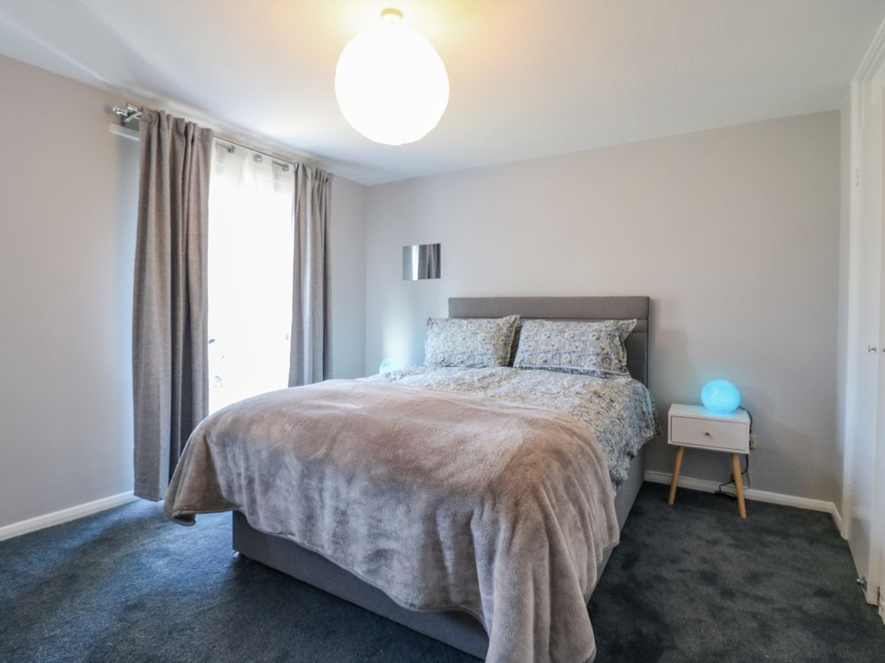 A bedroom with a bed and bedside table at Sea Rose Cottage