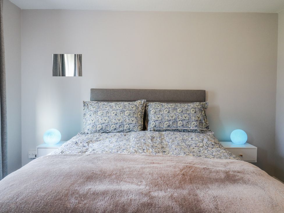 A bedroom with a bed and bedside tables at Sea Rose Cottage