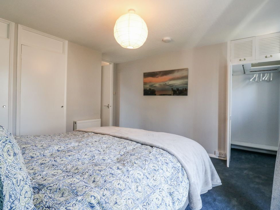A bedroom with a bed and wardrobe at Sea Rose Cottage