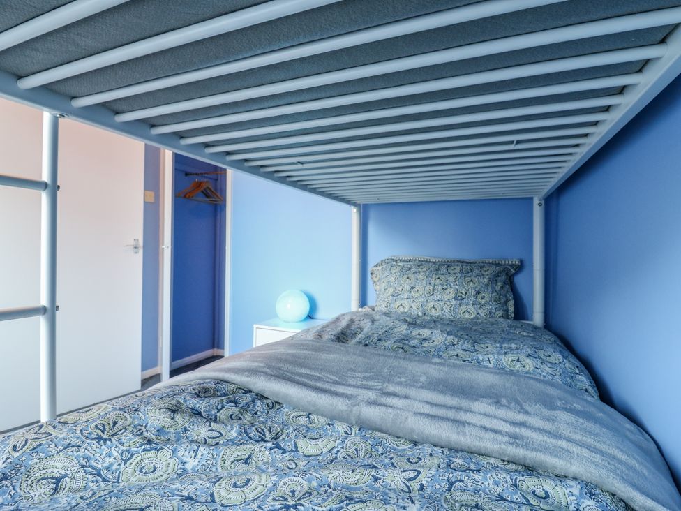 A bunk bed with bedding and nightstand in a bedroom at Sea Rose Cottage