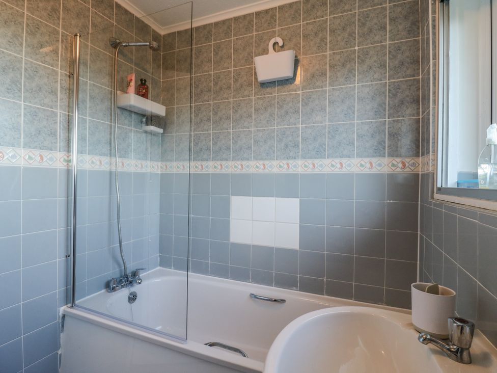 A bathroom with a bathtub and shower at Sea Rose Cottage