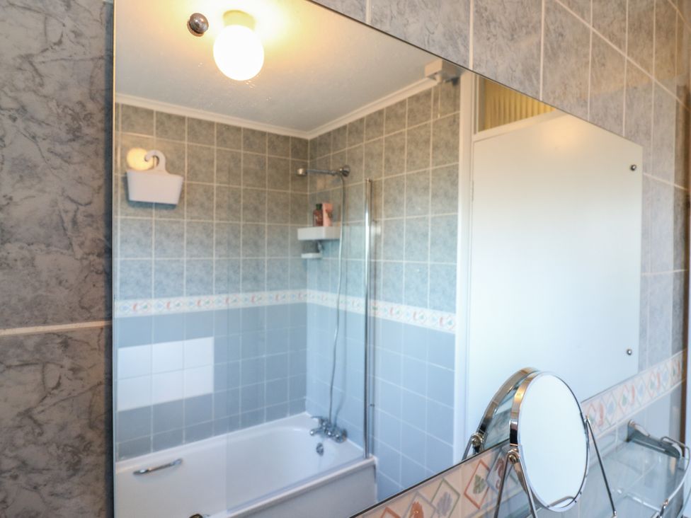 A bathroom with a bathtub and shower at Sea Rose Cottage