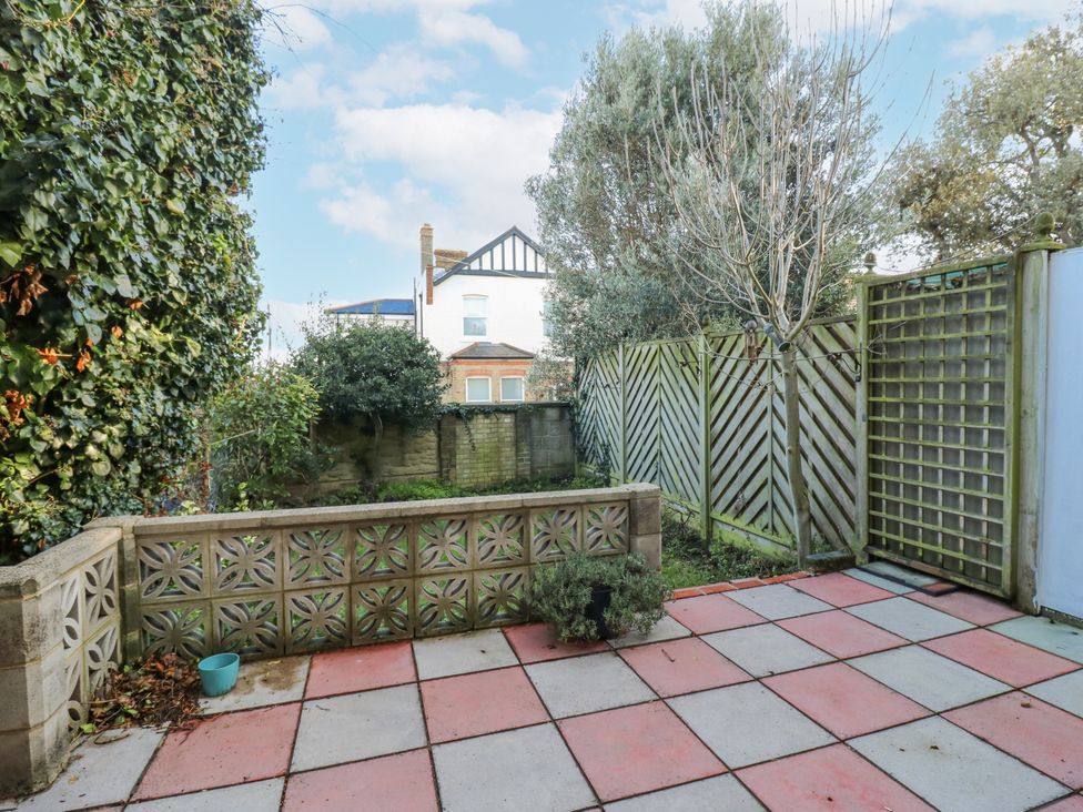 A garden with a fence and paving stones at Sea Rose Cottage