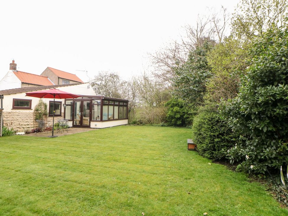 A garden with a conservatory and umbrella at Millers Retreat in Chesterfield