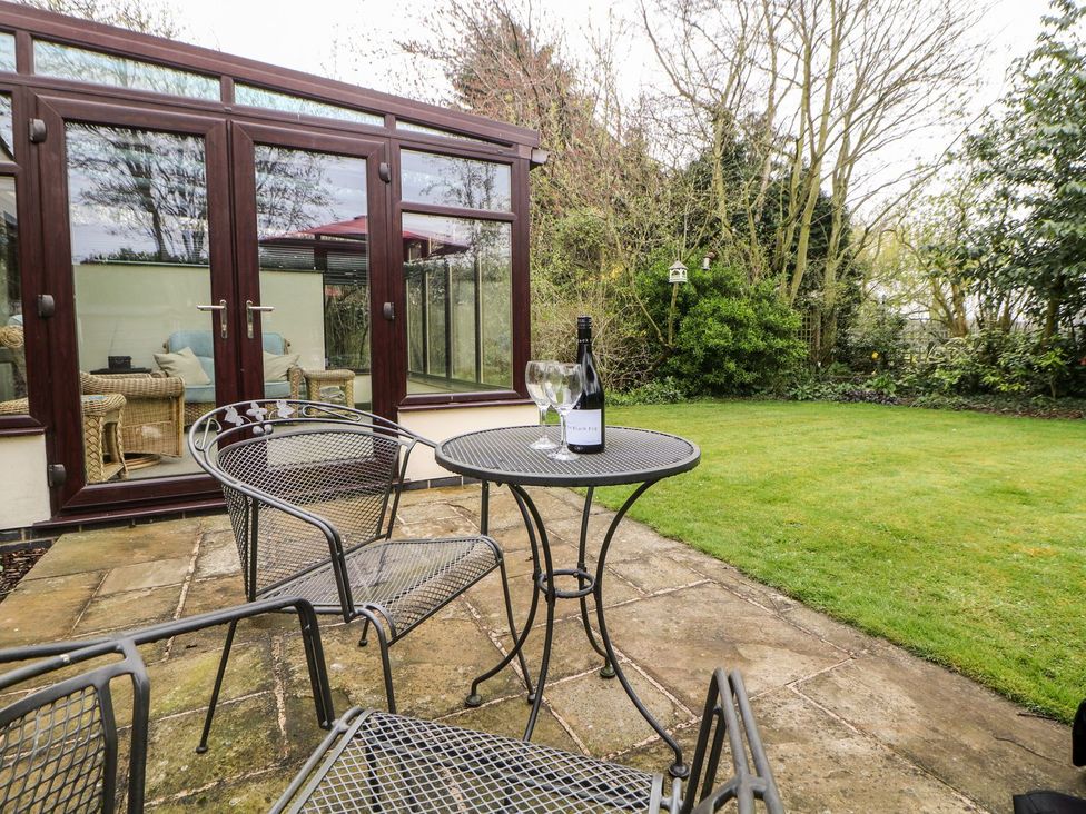 A garden with a table and chairs in front of a conservatory at Millers Retreat in Chesterfield