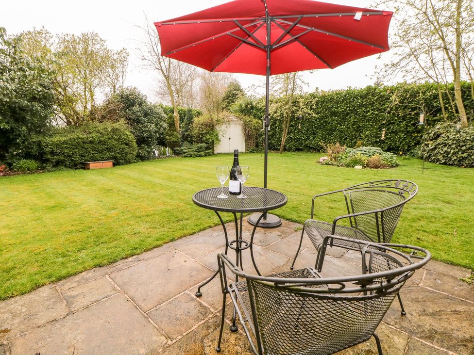 A garden with a table and chairs under an umbrella at Millers Retreat in Chesterfield