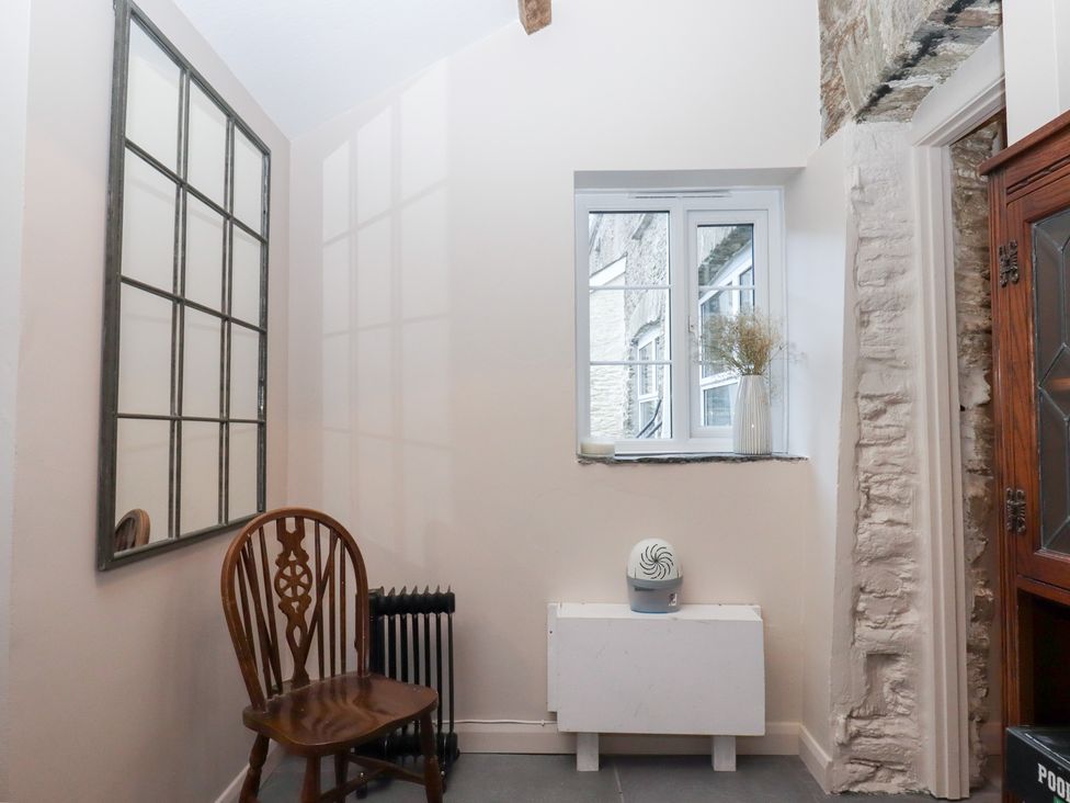 A hallway with a mirror, window, and chair at Garden Cottage at the Bowden Estate, Stoke Fleming