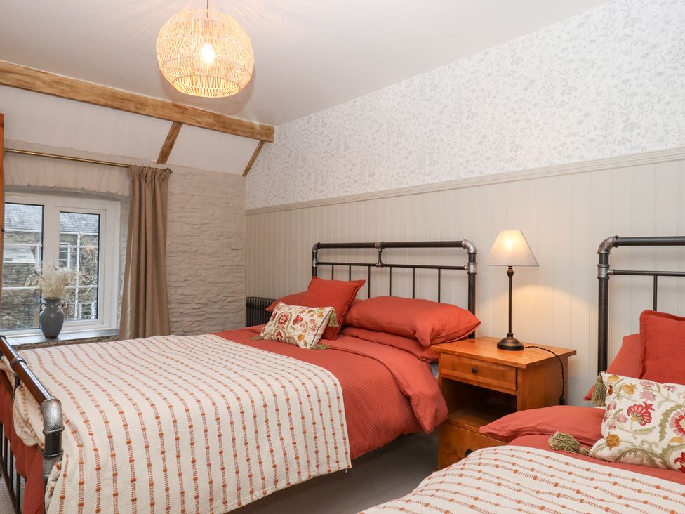 A bedroom with two beds and a lamp on a nightstand at Garden Cottage at the Bowden Estate Stoke Fleming