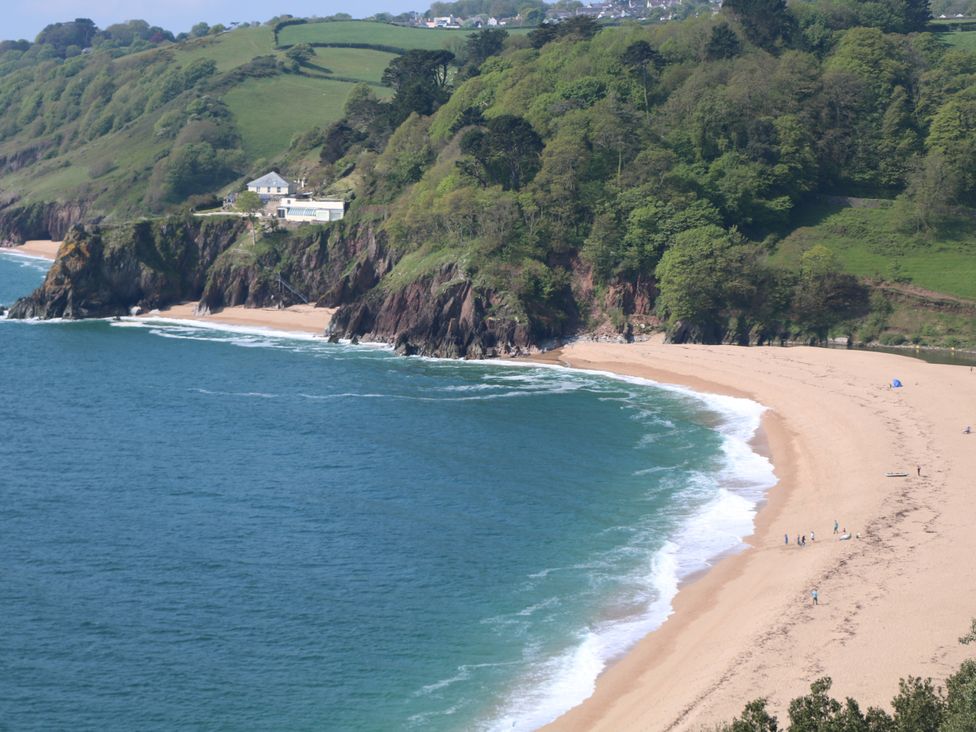 A beach with cliffs and people walking at Garden Cottage at the Bowden Estate Stoke Fleming