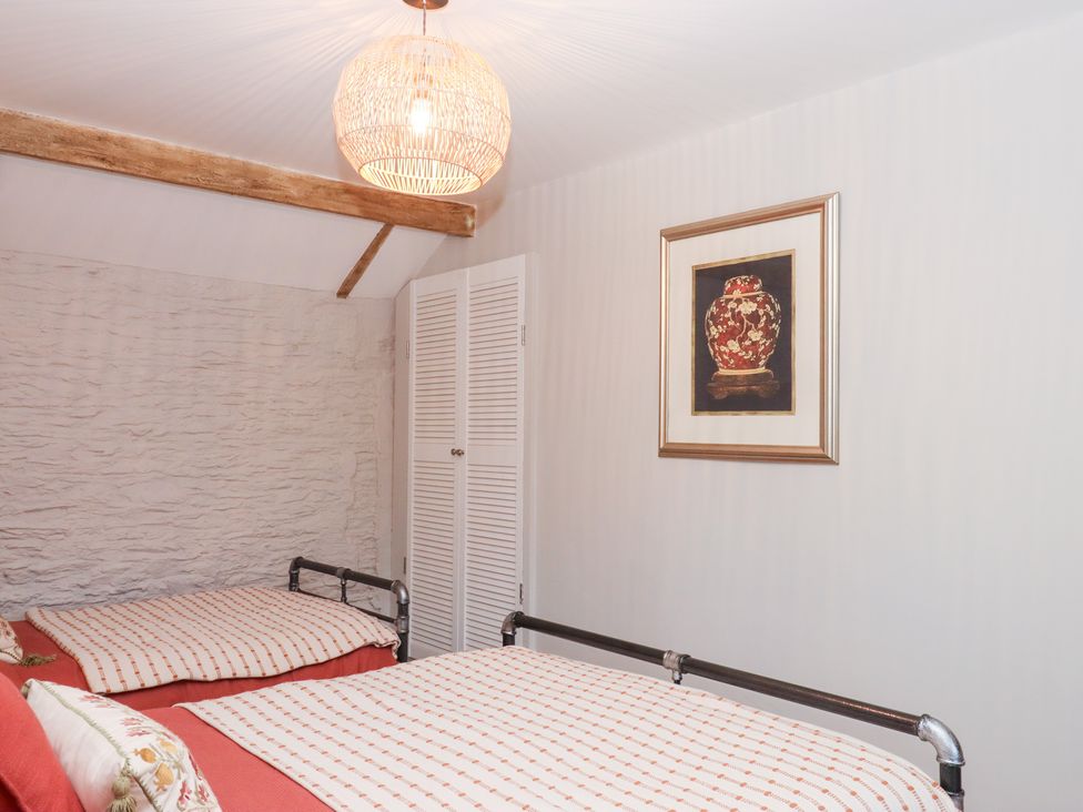 A bedroom with beds, closet, and wall art at Garden Cottage at the Bowden Estate, Stoke Fleming