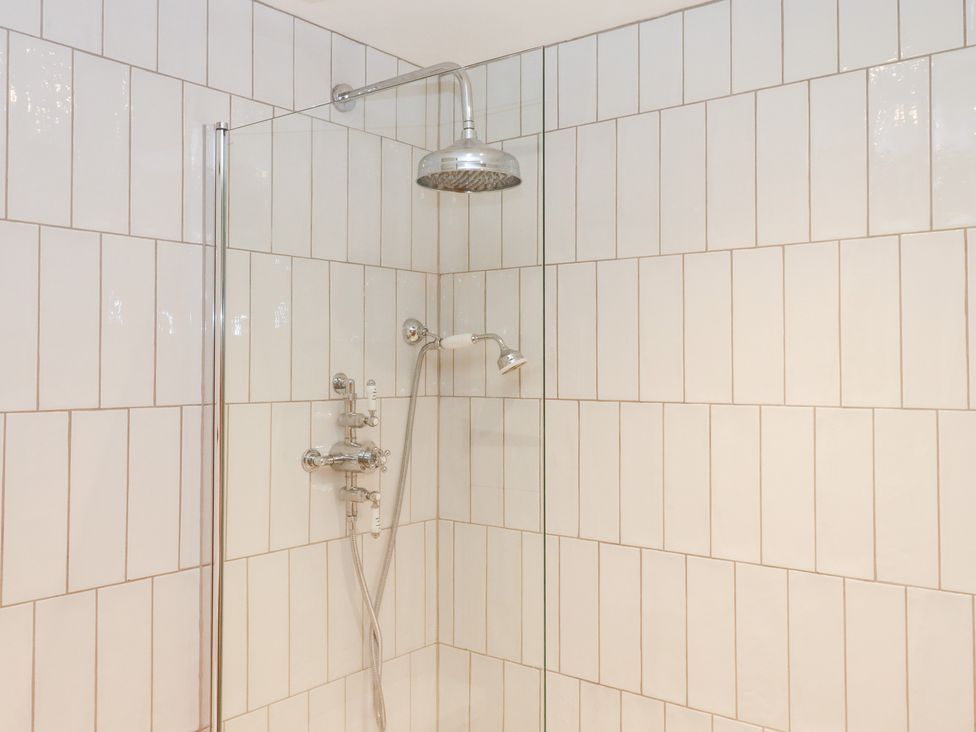 A shower with a glass door and tile walls at Garden Cottage at the Bowden Estate Stoke Fleming