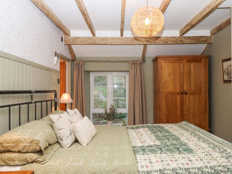 A bedroom with a bed and wardrobe at Garden Cottage at the Bowden Estate, Stoke Fleming