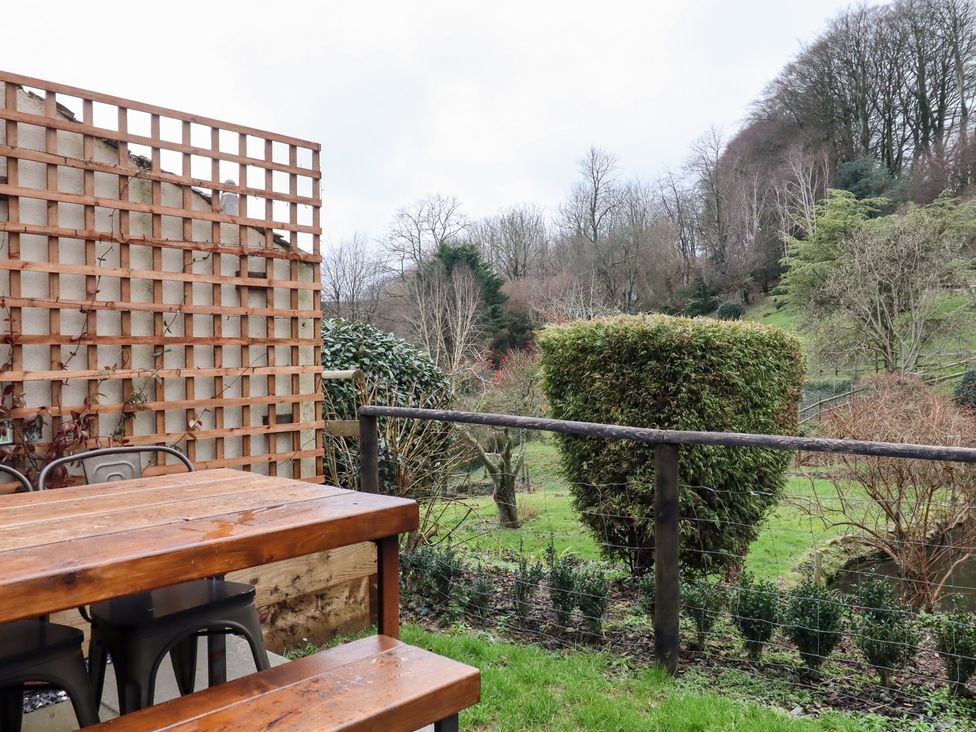 A garden with a wooden table and chairs at Garden Cottage at the Bowden Estate in Stoke Fleming