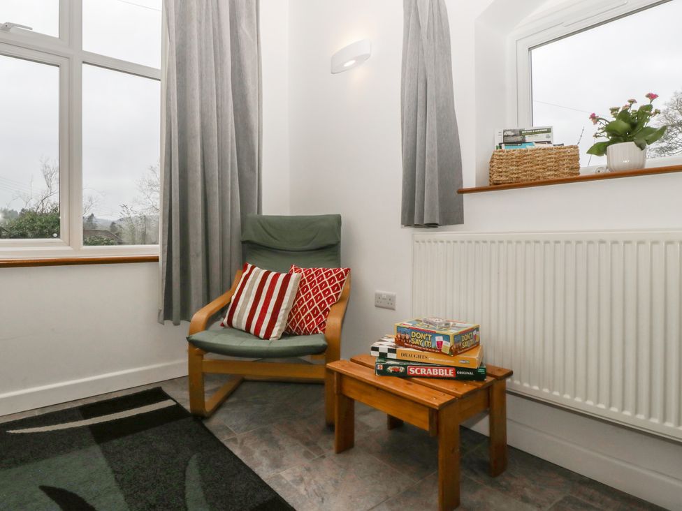 A sitting room with a chair and books on a table at Horse Gin in Lydney