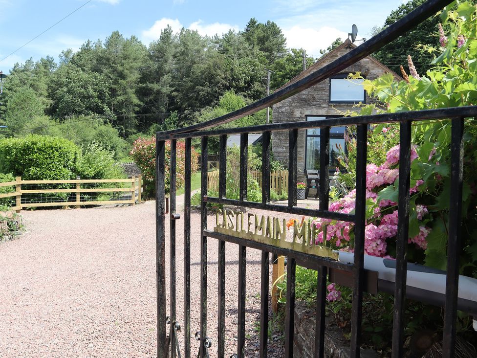 A gate leading to a garden with flowers and a house at Horse Gin in Parkend