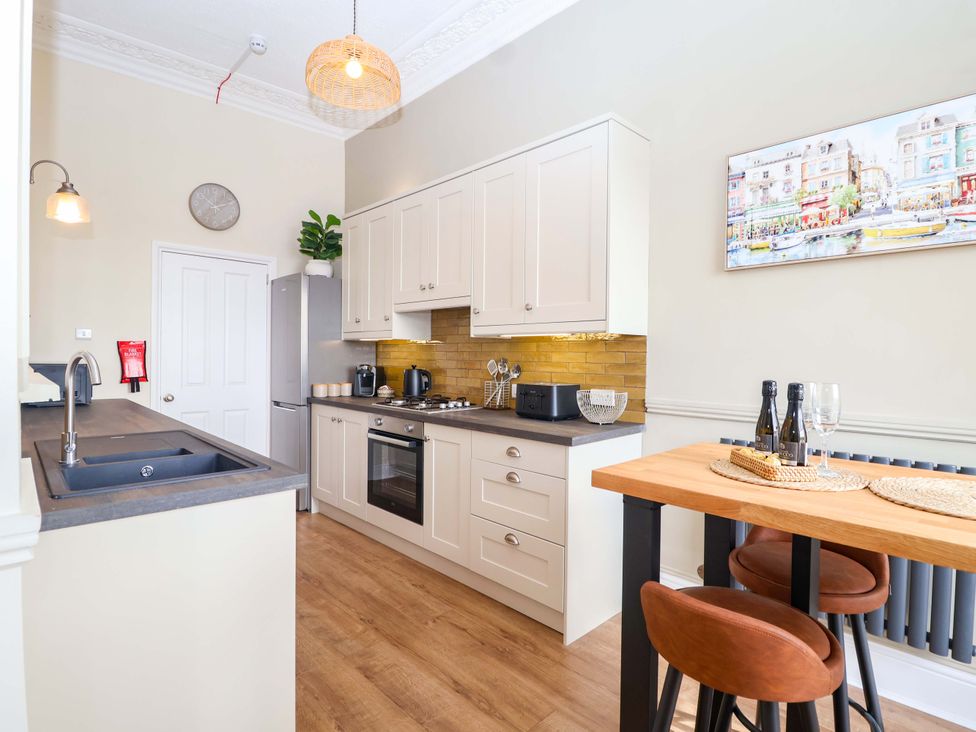 A kitchen with appliances and seating at Flat 2 The Moorings in Torquay