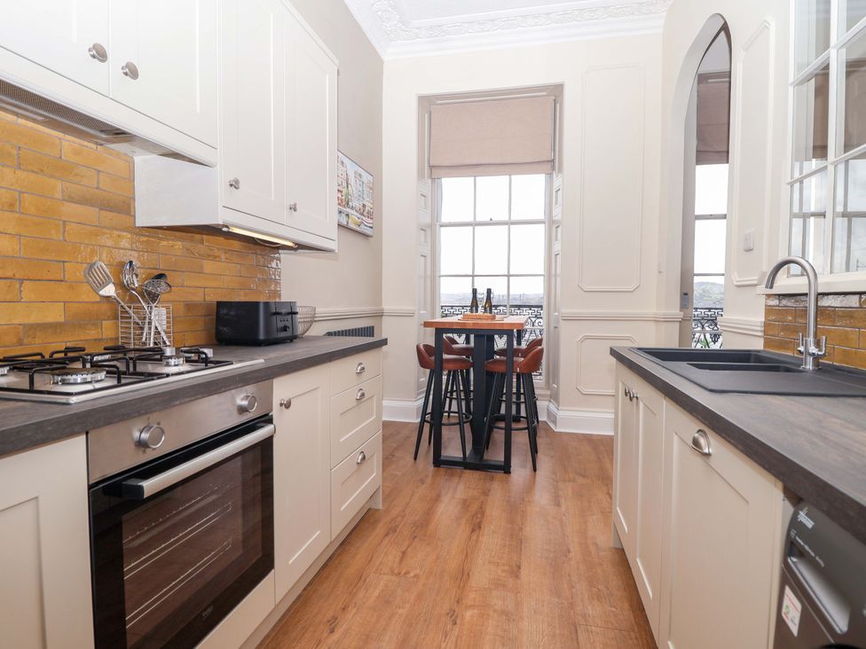A kitchen with a stove, oven, and bar table at Flat 2 The Moorings Torquay