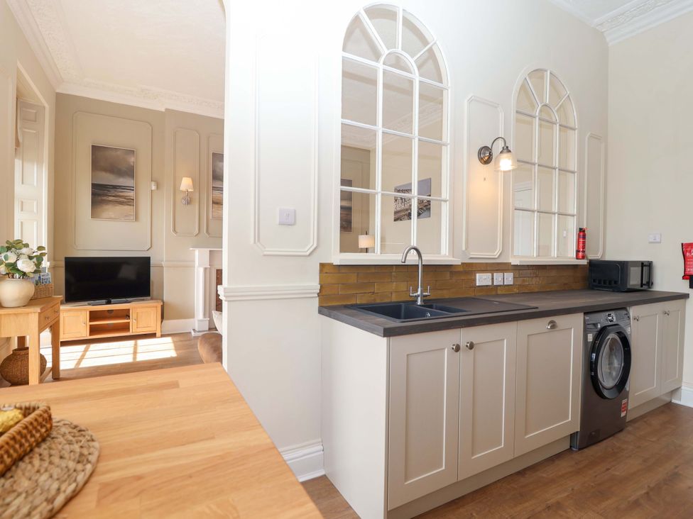 A kitchen with a washing machine and a television at Flat 2 The Moorings in Torquay